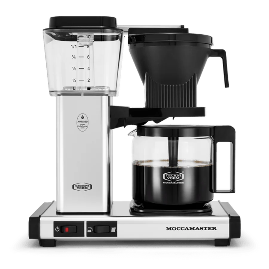 Technivorm Moccamaster KBGV Select 10-Cup coffee maker in Polished Silver on a clean kitchen counter, brewing into the glass carafe, the copper boiler housing visible through the machine body, a Specialty Coffee Association certification tag on the base -- the Dutch-made drip machine that has been Wirecutter's top pick for over a decade