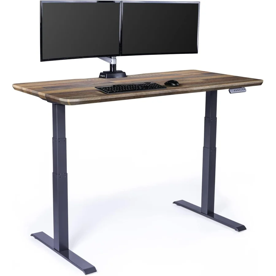 Vari Electric Standing Desk 60x30 with reclaimed wood desktop showing distinctive wood-grain pattern, dual-motor T-style frame in dark gray, memory preset controller integrated on the right edge of the desktop, set up with dual monitors — the 60-inch wide pick for ultrawide-plus-tower heavy setups